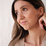 A fashionable woman donning a sweater and Cremilde Bispo Jewellery's Essential Twisted Hoops GP.