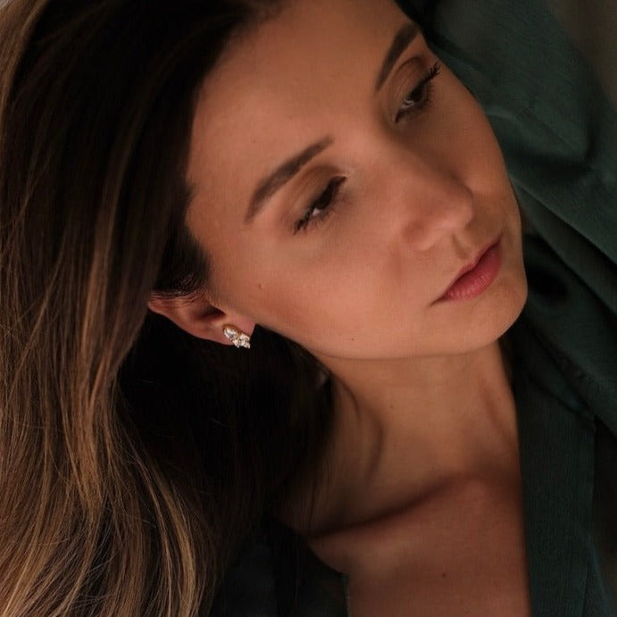 A woman in a green shirt showcasing her jewelry collection, including the Essential Drops earrings from Cremilde Bispo Jewellery.