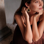 A woman in a brown dress is posing for a photo, showcasing her opulence with the stunning Cremilde Bispo Jewellery's Garden's Delight II GP earring set.
