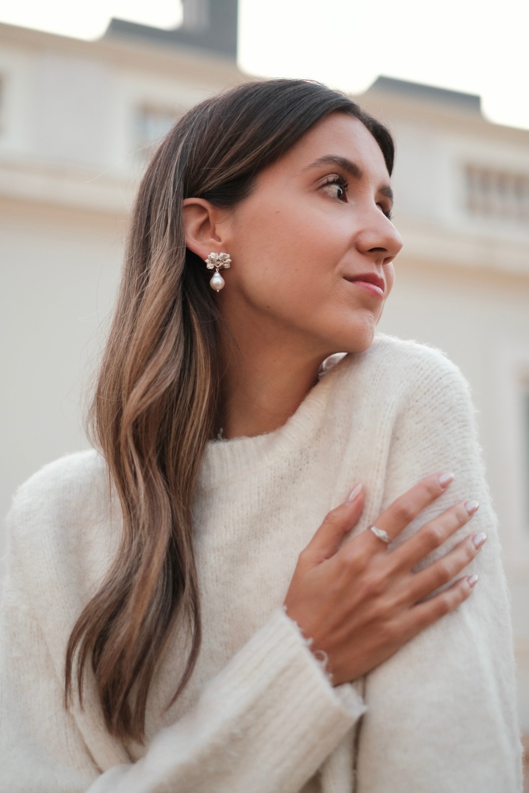 A woman wearing a white sweater and Cremilde Bispo Jewellery's The Pearly Forest Earrings.