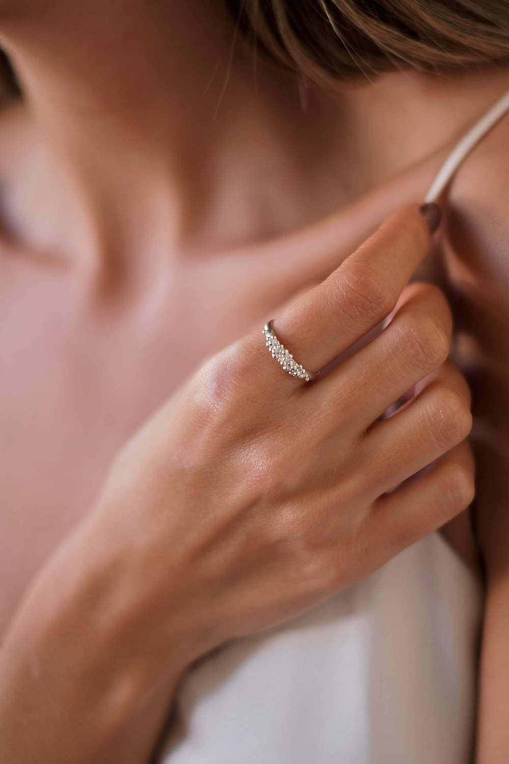 A woman exuding timeless elegance as she proudly displays her Cremilde Bispo Jewellery's Essential Dot Ring, a sparkling white diamond masterpiece that effortlessly adds an extra touch of effortless chic to any ensemble.