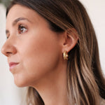 A woman showcasing timeless elegance with her Cremilde Bispo Jewellery Essential Leaf Hoops GP earrings.
