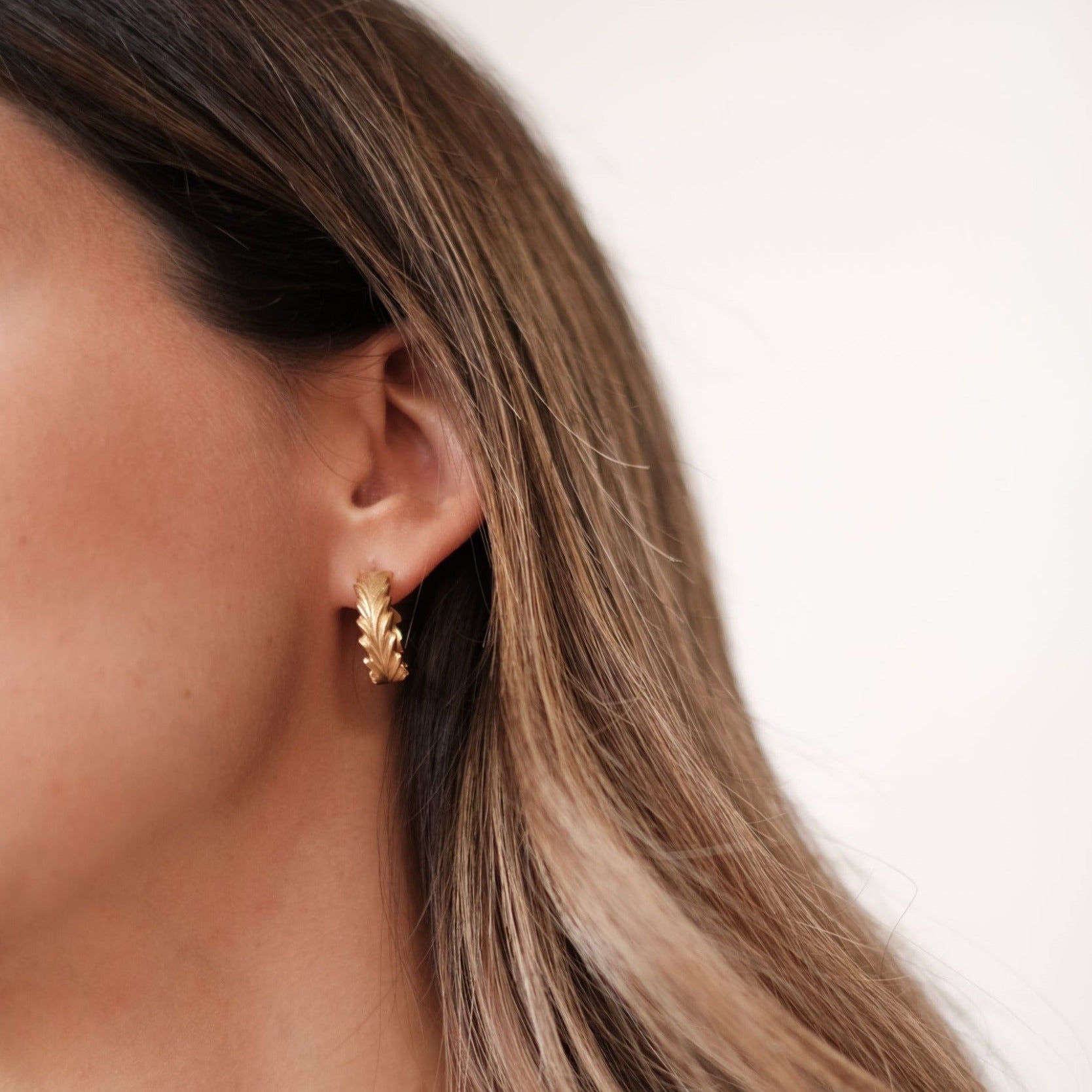 A woman's ear adorned with timeless elegance, flaunting Cremilde Bispo Jewellery's Essential Leaf Hoops GP for an exclusive touch.