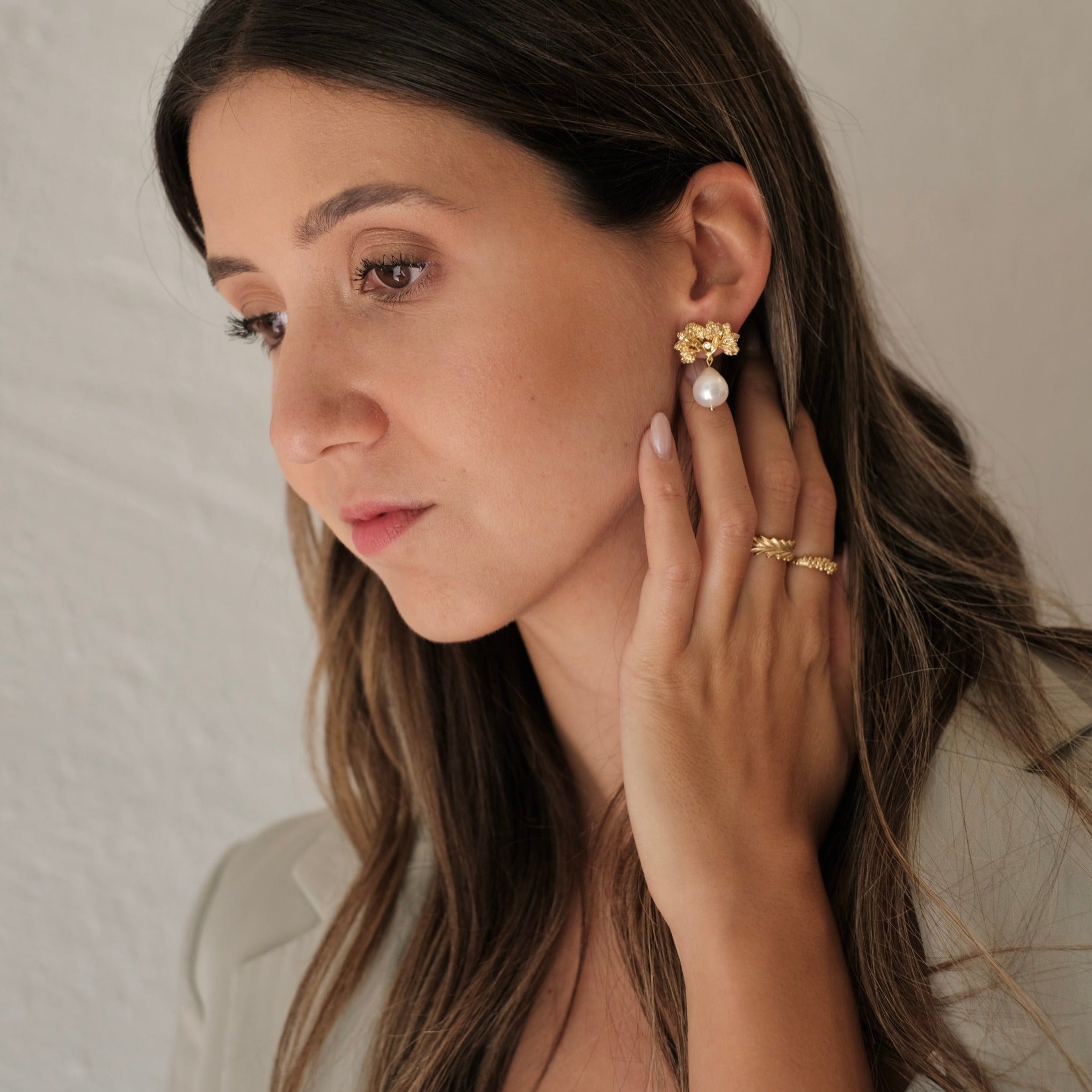 A woman wearing The Pearly Forest Earrings GP by Cremilde Bispo Jewellery and a blazer.
